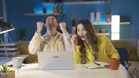 Happy-couple-working-together-in-home-office.--Young-man-with-good-news.